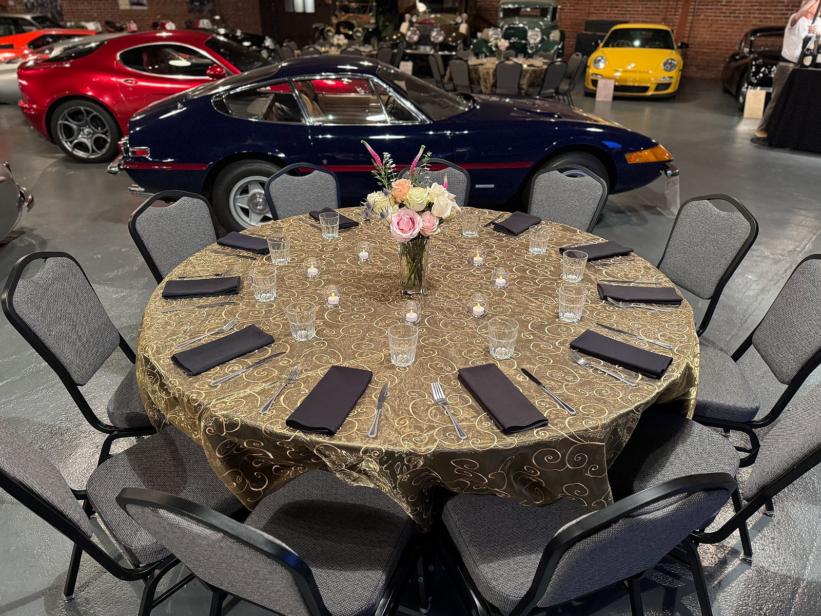 A single round table in gold organza beside a Ferrari Daytona