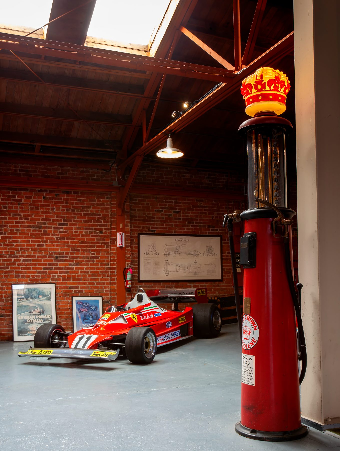 Niki Lauda's Ferrari Formula One car beside a vintage Red Crown gas pump in the brick room